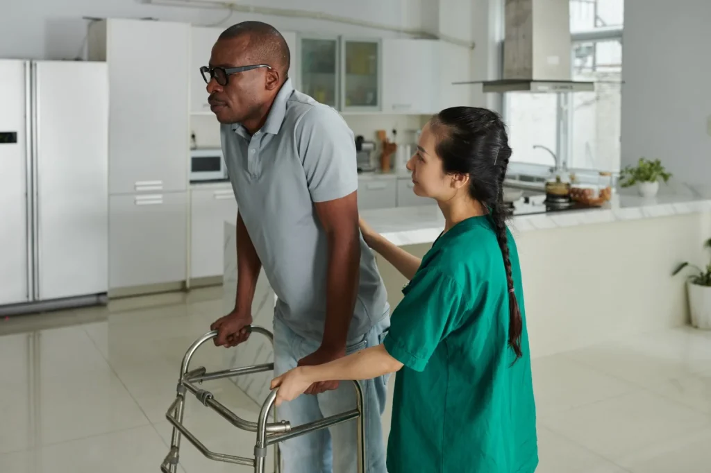 Disabled man using walker with support from nurse