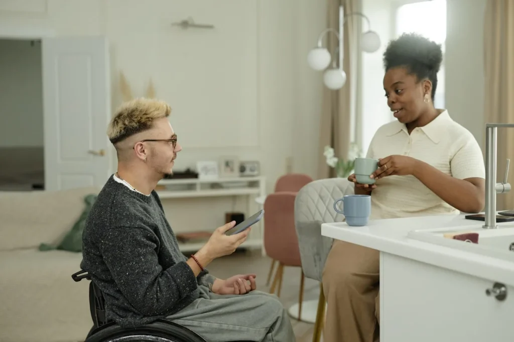 Disabled man in wheelchair talking with support worker at home