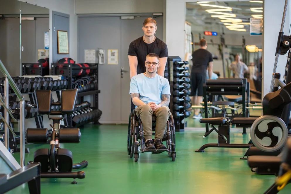 Disabled man in wheelchair at gym with support worker