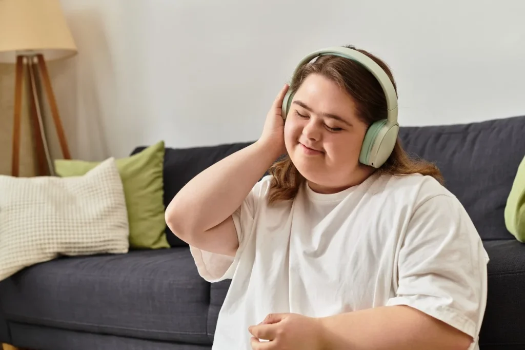 Disabled woman with down syndrome smiling while listening to music through headphones
