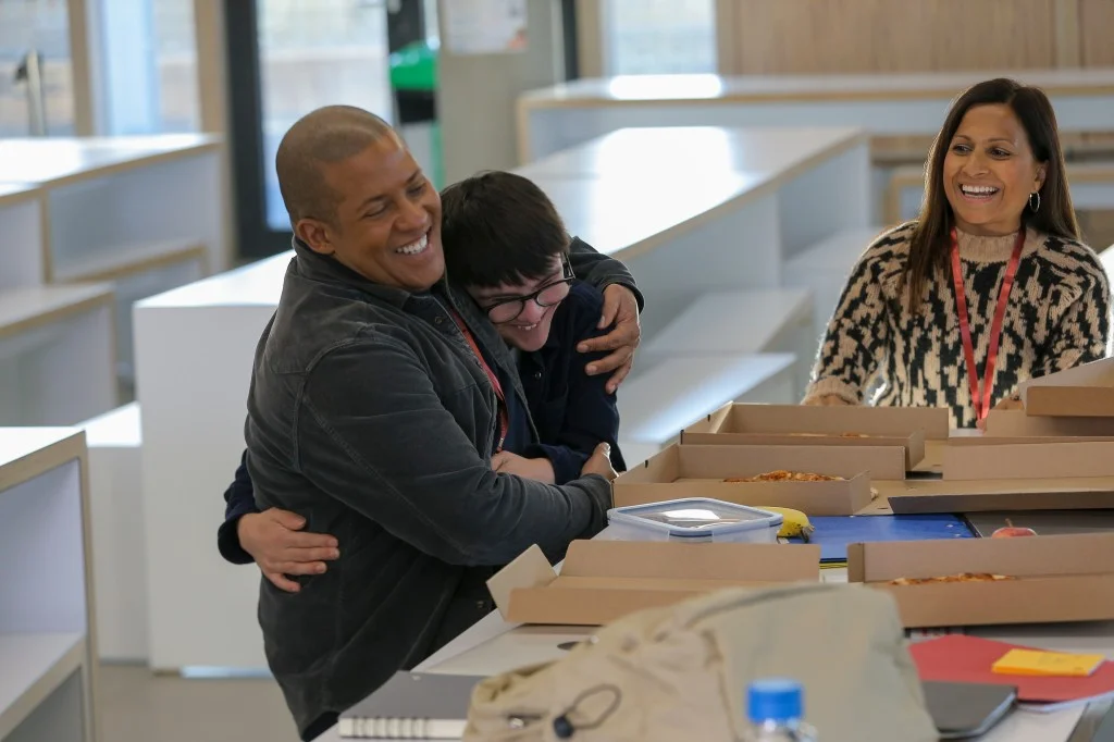 Support worker and disabled man hugging and laughing while eating pizza
