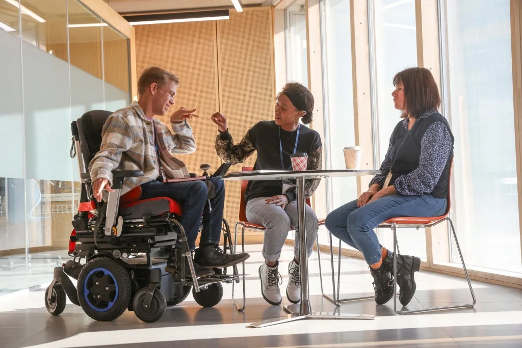 Two disabled people smiling and talking with support worker